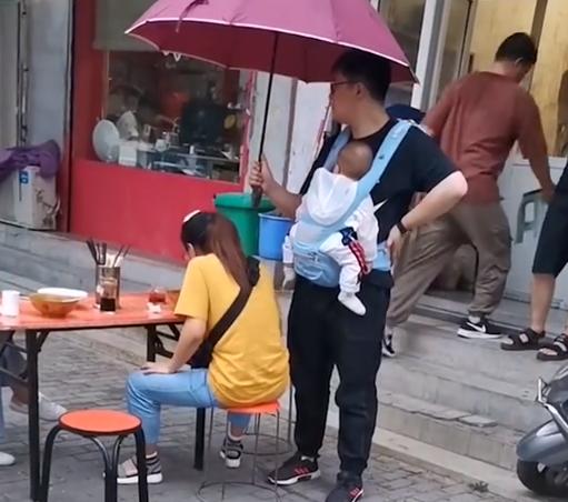 妻子雨中吃面丈夫身旁打伞 看那个老公的面相就感觉是个好老公！
