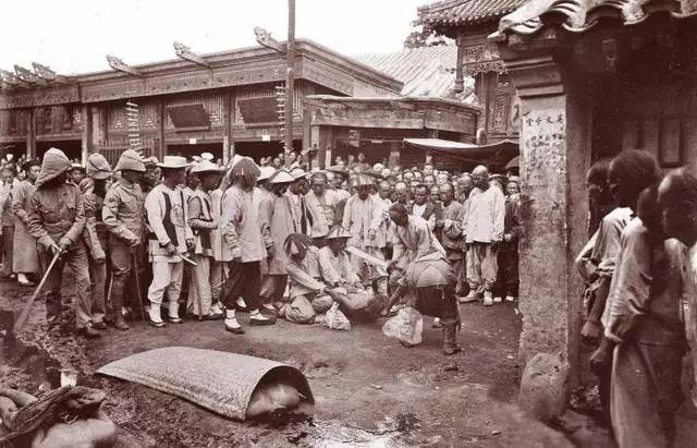 晚清老照片：刽子手在北京菜市口行刑，贵妇端着枪坐在地上射击