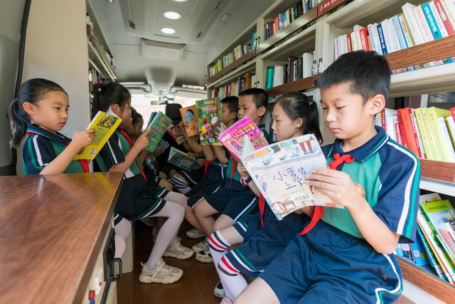 呼和浩特市玉泉区恒昌店巷小学的孩子们在"流动图书车"内翻阅图书