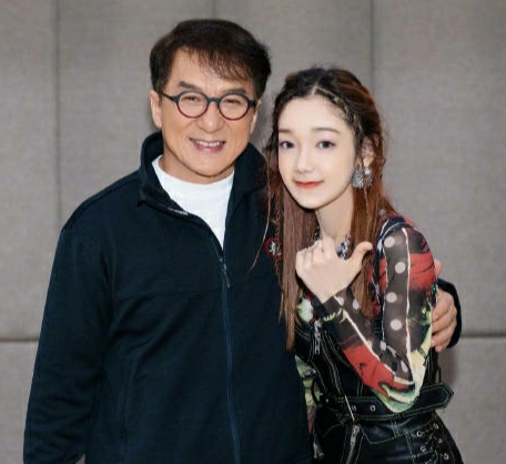 成龙与女团合影略显亲密，搭肩搂腰被批行为不当，表情像复制粘贴