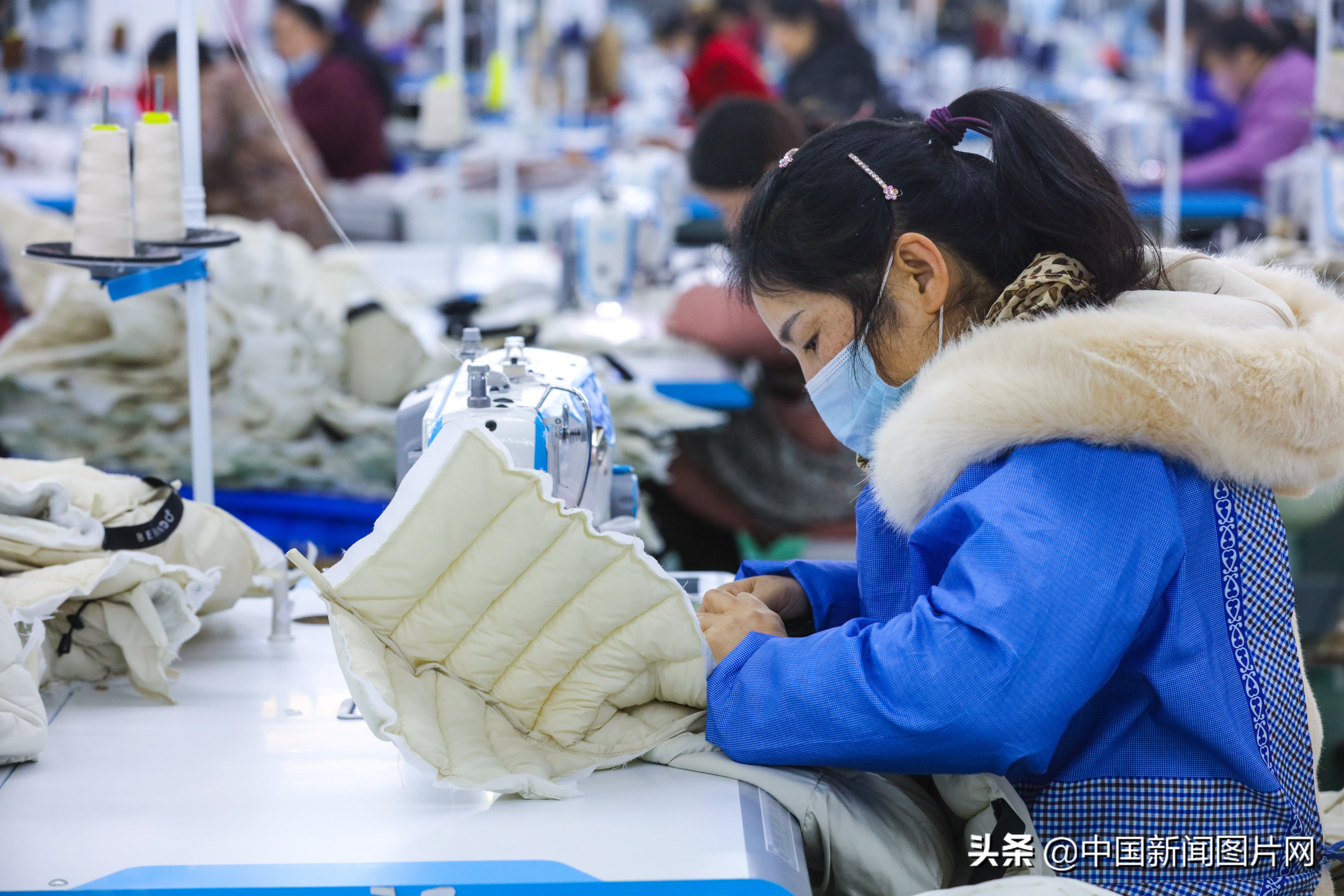 市光山县产业集聚区的良友服饰扶贫车间里工人正在赶做客户订单羽绒服