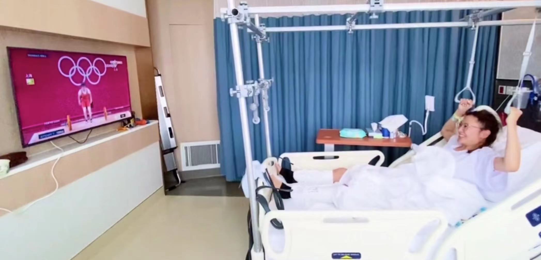 38岁应采儿双腿打石膏，半卧病床进行康复训练，病房内追看奥运会