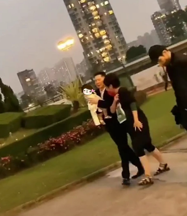 向华强祖孙三代在公园散步，向佐帮郭碧婷拎鞋