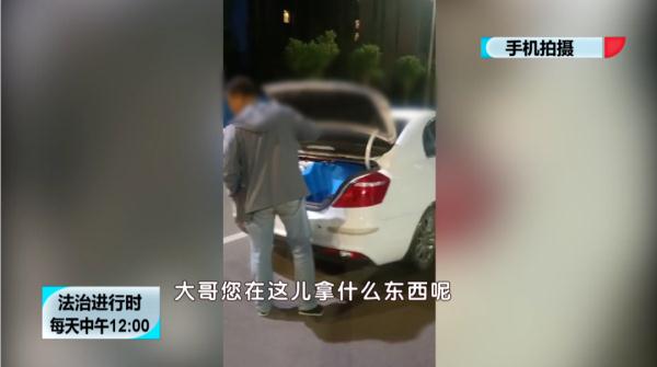 小偷打开轿车后备箱行窃，车主在身后举手机淡定拍摄