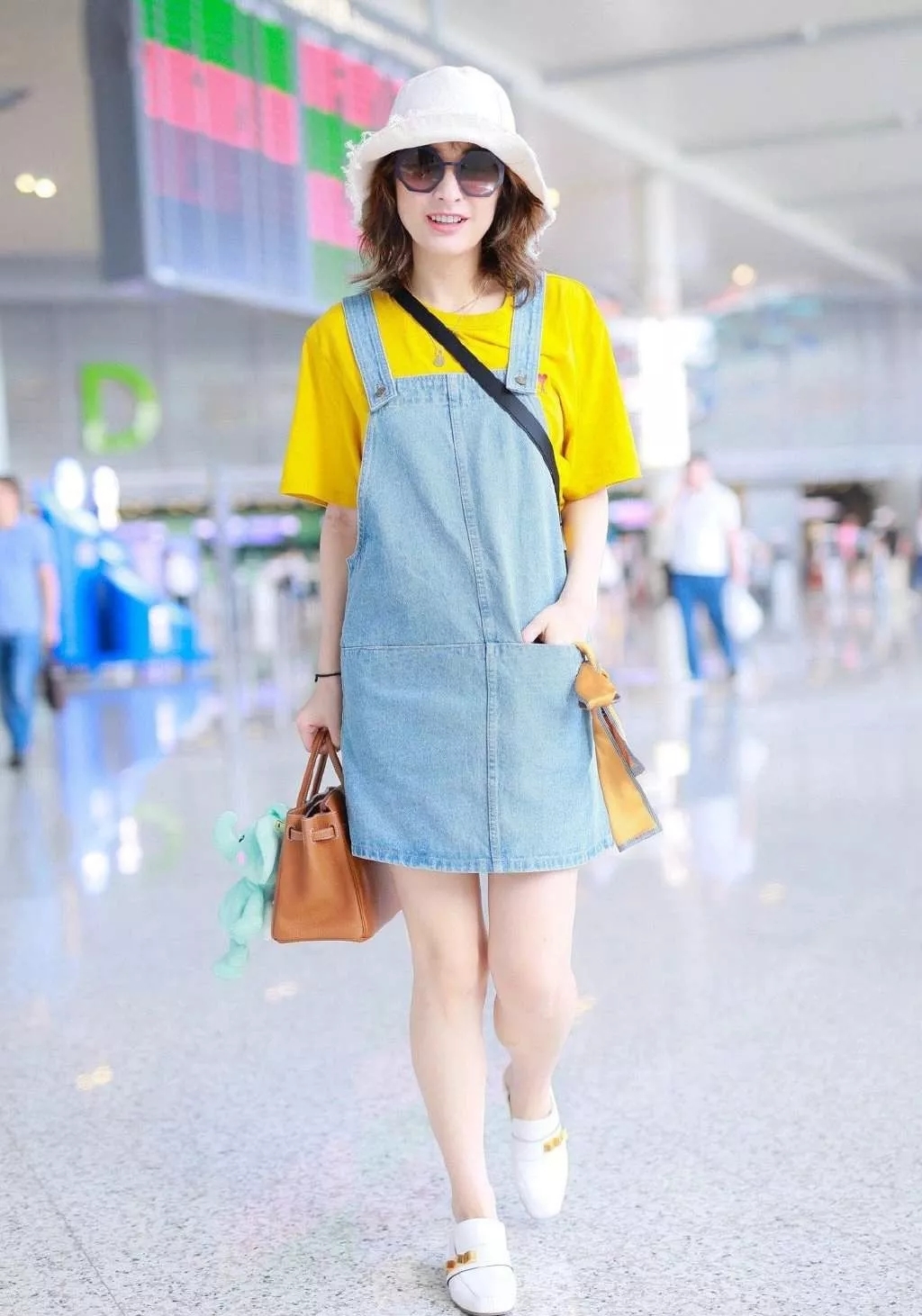 吴昕机场街拍照，黄T背带裙尽显纤细身材，头戴渔夫帽青春气息足