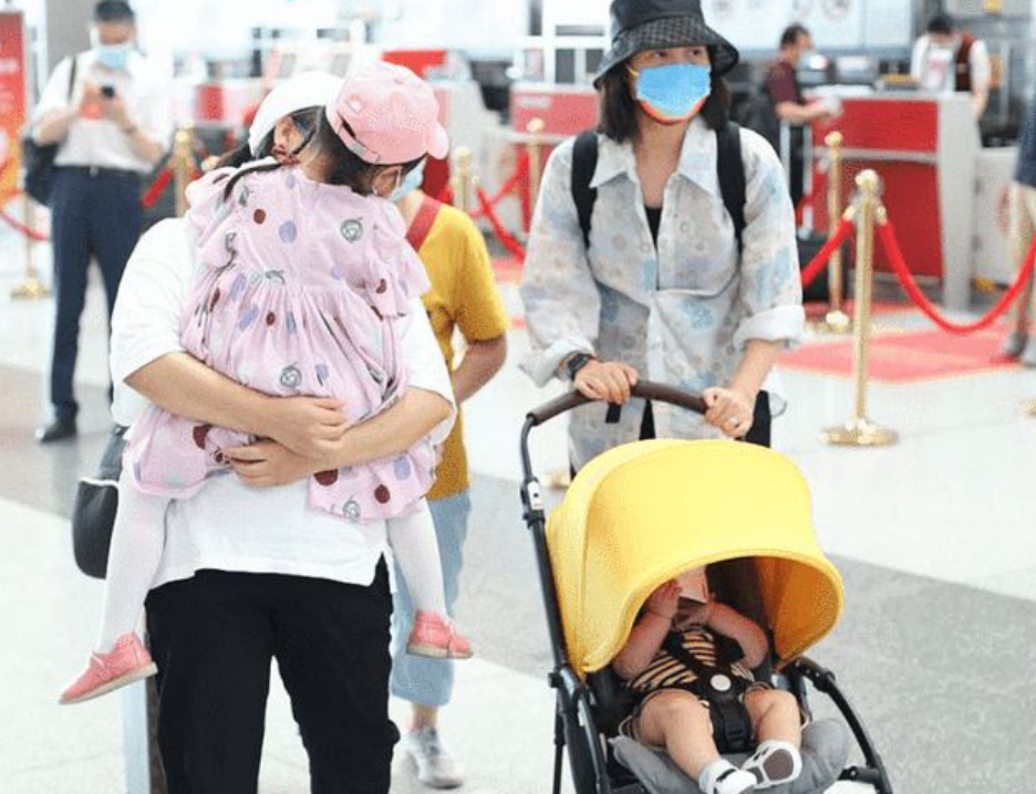 朱丹带一双儿女赶飞机，不时低头看孩子，却不见丈夫周一围的身影